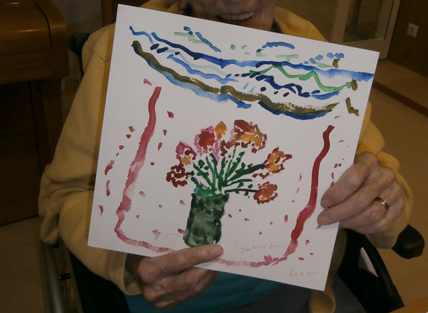 alte Frauenhände halten ein Bild mit Blumen in einer Vase hoch